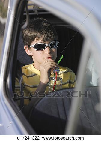 Boy (8-10) in sunglasses sitting in backseat of car, drinking through straw View Large Photo Image Stock Image - Boy (8-10) in sunglasses sitting in backseat of car, drinking through straw. Fotosearch