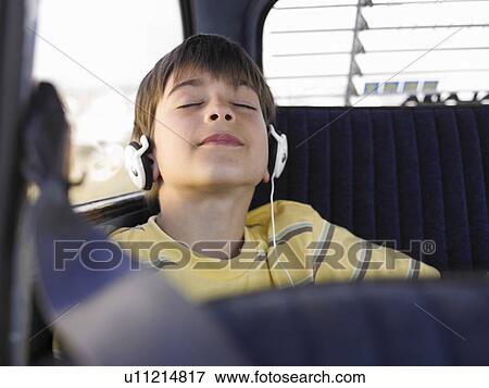 Boy (8-10) listening to music with headphones in backseat of car, eyes closed View Large Photo Image Stock Photo - Boy (8-10) listening to music with headphones in backseat of car, eyes closed. Fotosearch