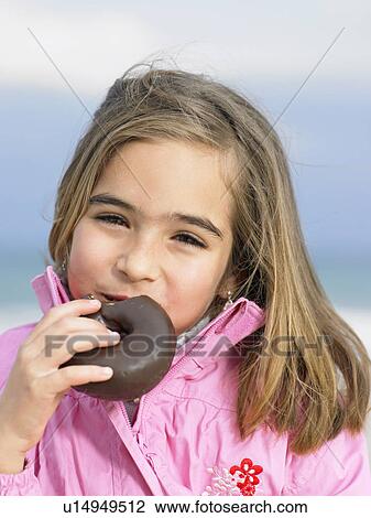 Girl (6-8) eating chocolate doughnut, portrait, close-up View Large Photo Image Stock Image - Girl (6-8) eating chocolate doughnut, portrait, close-up. Fotosearch