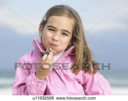Stock Photo - Girl (6-8) eating chocolate doughnut, portrait, close-up. Fotosearch