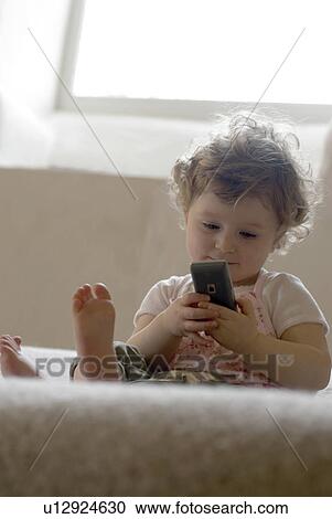 Girl (9-12 months) using mobile phone. View Large Photo Image Stock Image - Girl (9-12 months) using mobile phone.. Fotosearch
