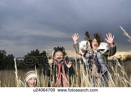 Stock Photo - Group of kids jumping in long grass.. Fotosearch