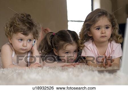 Three little girls (9-12 months, 2-4 ) using mobile phone and laptop. View Large Photo Image Stock Photograph - Three little girls (9-12 months, 2-4 ) using mobile phone and laptop.. Fotosearch