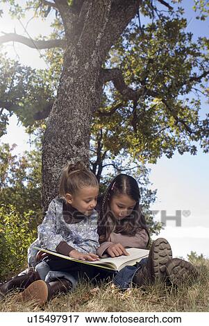 Stock Photo - Two young girls reading a book.. Fotosearch