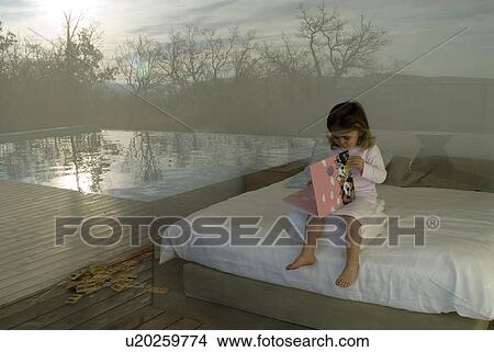 Picture - View through window of girl (2-4) reading book.. Fotosearch