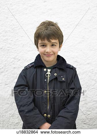 Young boy (6-8) standing in front of a white wall View Large Photo Image Picture - Young boy (6-8) standing in front of a white wall. Fotosearch