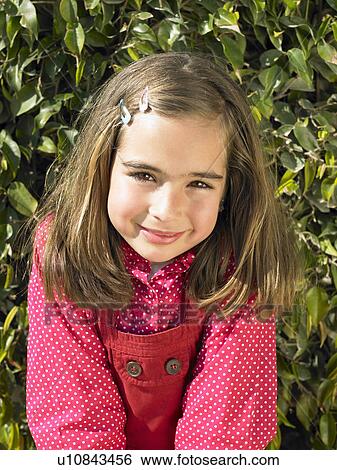 Young girl (5-7) against hedge, portrait View Large Photo Image Stock Photograph - Young girl (5-7) against hedge, portrait. Fotosearch