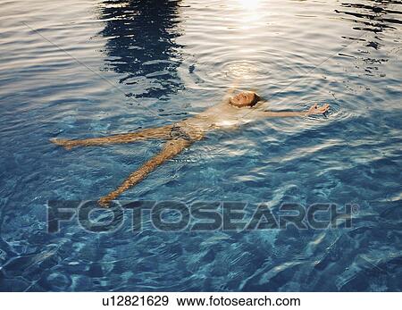 Stock Photo - Young girl floating on back in pool smiling.. Fotosearch