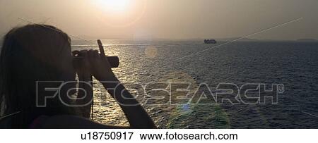 Stock Photo - Young girl using binoculars to look at a boat in the water.. Fotosearch
