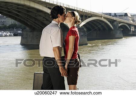 Couple kissing by a bridge. View Large Photo Image Stock Photo - Couple kissing by a bridge.. Fotosearch
