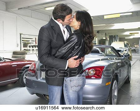 Couple kissing in front of a convertible in a garage. View Large Photo Image Picture - Couple kissing in front of a convertible in a garage.. Fotosearch