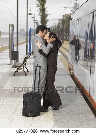 Couple wearing business suits kissing each other on platform next to static train/tram View Large Photo Image Stock Photograph - Couple wearing business suits kissing each other on platform next to static train/tram. Fotosearch
