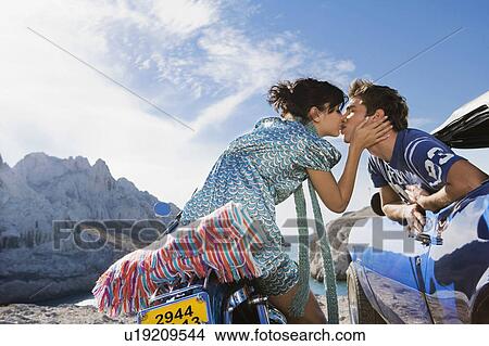 Picture - Man in car woman on motorbike kissing.. Fotosearch