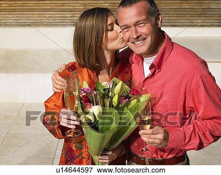 Stock Photo - Woman kissing mature man on cheek. Fotosearch