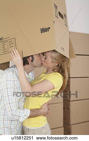Young couple embracing and kissing under cardboard box View Large Photo Image Stock Image - Young couple embracing and kissing under cardboard box. Fotosearch