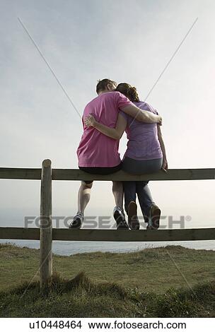 A Couple hug sitting on a country fence. View Large Photo Image Picture - A Couple hug sitting on a country fence.. Fotosearch