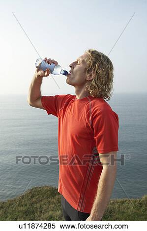 A young Male runner drinks from a bottle. View Large Photo Image Stock Photography - A young Male runner drinks from a bottle.. Fotosearch