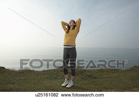 Stock Image - A young Woman stretching in a seascape.. Fotosearch