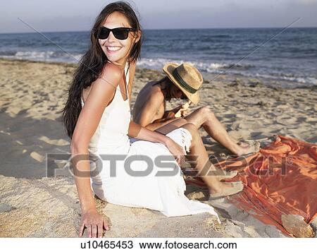 Man playing a ukulele on the beach while a smiling woman looks over her shoulder. View Large Photo Image Stock Image - Man playing a ukulele on the beach while a smiling woman looks over her shoulder.. Fotosearch