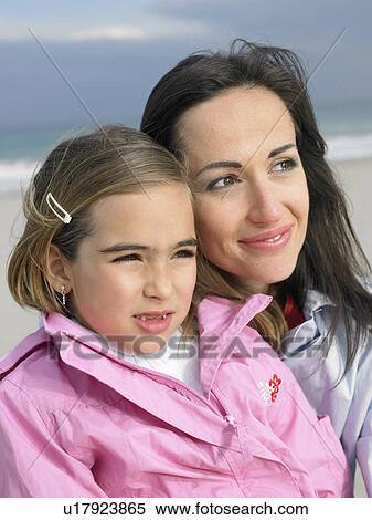 Stock Photography - Mother and daughter (6-8) on beach, close-up. Fotosearch