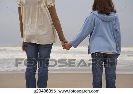 Mother and daughter (9-11) holding hands on beach, rear view View Large Photo Image Stock Photography - Mother and daughter (9-11) holding hands on beach, rear view. Fotosearch