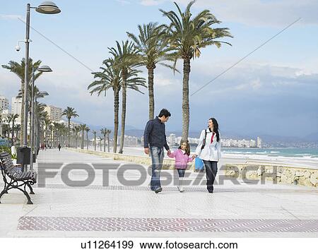 Mother and father walking along palm lined pavement by the sea with young daughter (6-8). Alicante, Spain. View Large Photo Image Stock Photo - Mother and father walking along palm lined pavement by the sea with young daughter (6-8). Alicante, Spain.. Fotosearch