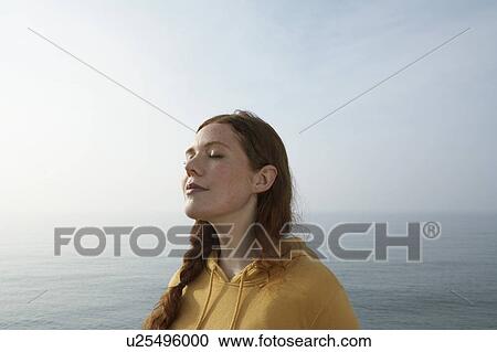 Stock Image - Profile of a young woman by the sea.. Fotosearch