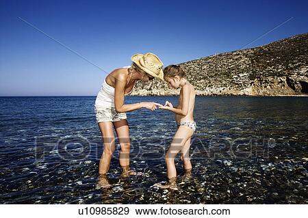 Woman and young girl at the beach looking at pebbles. View Large Photo Image Stock Photo - Woman and young girl at the beach looking at pebbles.. Fotosearch