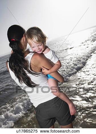 Stock Photography - Woman holding a smiling young girl at the beach.. Fotosearch
