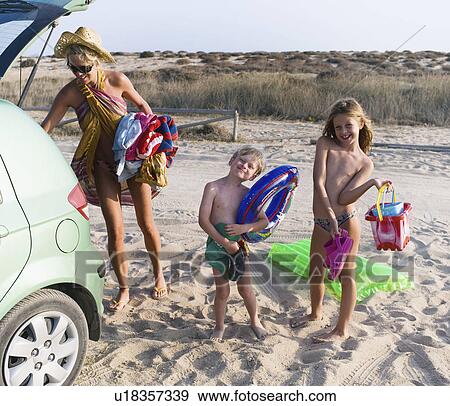 Stock Photo - Woman with young boy and young girl arriving the beach.. Fotosearch
