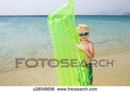 Young boy at the beach with an inflatable raft. View Large Photo Image Stock Photo - Young boy at the beach with an inflatable raft.. Fotosearch