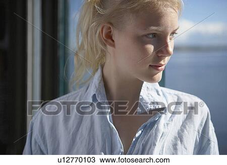 Stock Image - Young woman by windows of beach house.. Fotosearch
