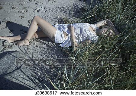 Stock Photo - Young woman lying in long grass.. Fotosearch