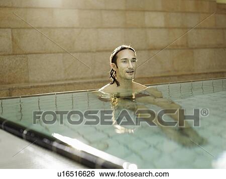 Stock Photograph - Mature man sitting in swimming pool, portrait. Fotosearch