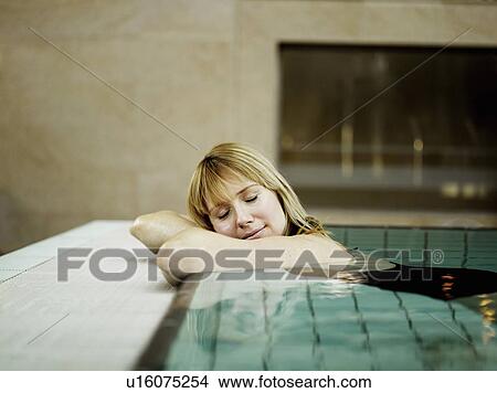 Woman relaxing by poolside, eyes closed View Large Photo Image Picture - Woman relaxing by poolside, eyes closed. Fotosearch