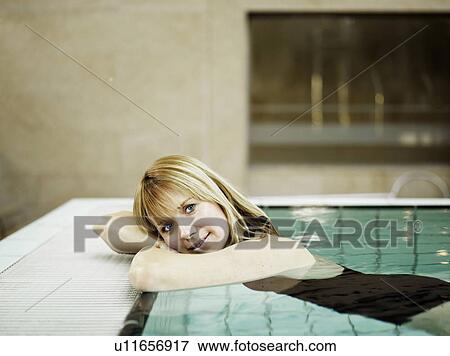 Stock Photo - Woman relaxing by poolside, smiling, portrait. Fotosearch