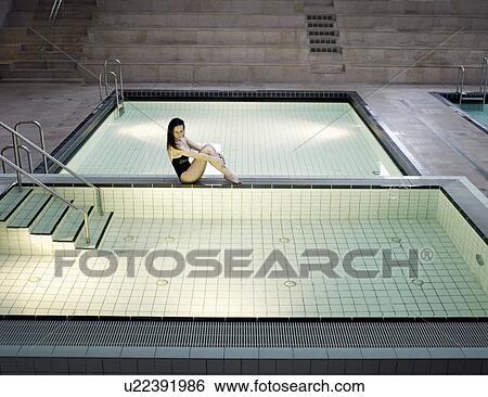 Stock Photograph - Woman sitting at poolside. Fotosearch