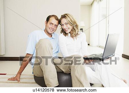 Happy couple at home with laptop View Large Photo Image Stock Photo - Happy couple at home with laptop. Fotosearch