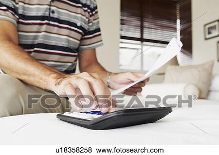 Male's hand adds up bills on calculator View Large Photo Image Stock Photo - Male's hand adds up bills on calculator. Fotosearch