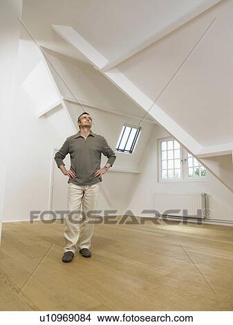Picture - Man looking up inside empty white loft.. Fotosearch