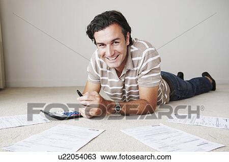 Stock Image - Man works on home finance. Fotosearch