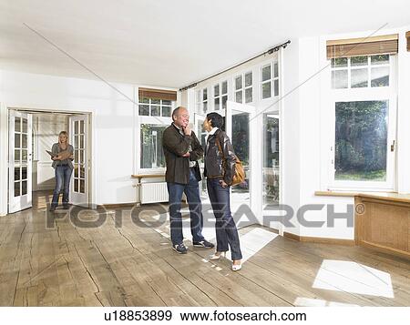 Real estate agent showing empty house to a couple. View Large Photo Image Stock Photo - Real estate agent showing empty house to a couple.. Fotosearch