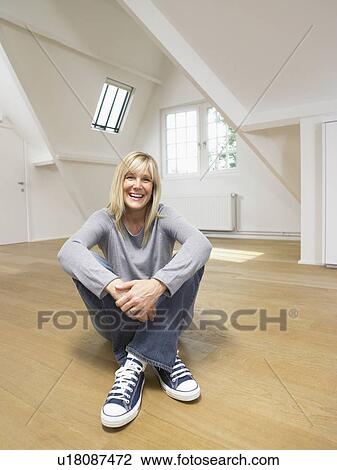Smiling seated woman on wooden floor of empty white loft. Legs crossed. View Large Photo Image Stock Image - Smiling seated woman on wooden floor of empty white loft. Legs crossed.. Fotosearch