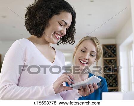 Two women using calculator at home View Large Photo Image Stock Photo - Two women using calculator at home. Fotosearch