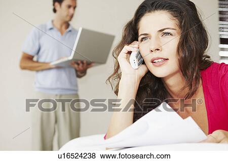 Stock Photo - Woman on phone with bills and male. Fotosearch