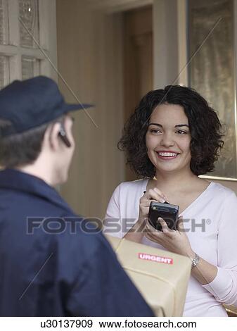 Stock Photo - Woman signing for package with courier. Fotosearch