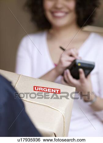 Woman signing for urgent delivery View Large Photo Image Stock Photograph - Woman signing for urgent delivery. Fotosearch