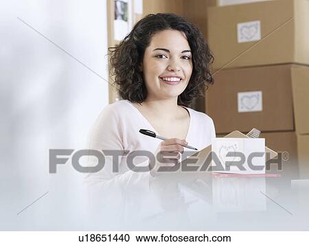 Stock Image - Woman with clipboard in front of boxes. Fotosearch