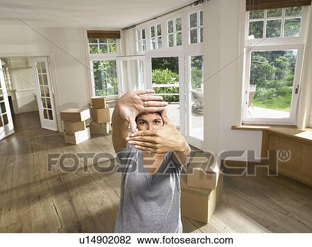 Women framing face while moving into empty house. View Large Photo Image Stock Image - Women framing face while moving into empty house.. Fotosearch