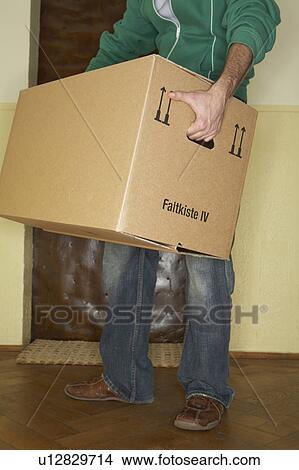 Young man carrying large cardboard box, low section View Large Photo Image Picture - Young man carrying large cardboard box, low section. Fotosearch
